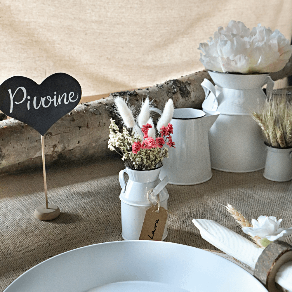 Jute tafelloper bedekt met bloemen, een wit bord en een houten bordje met een krijten hard erop