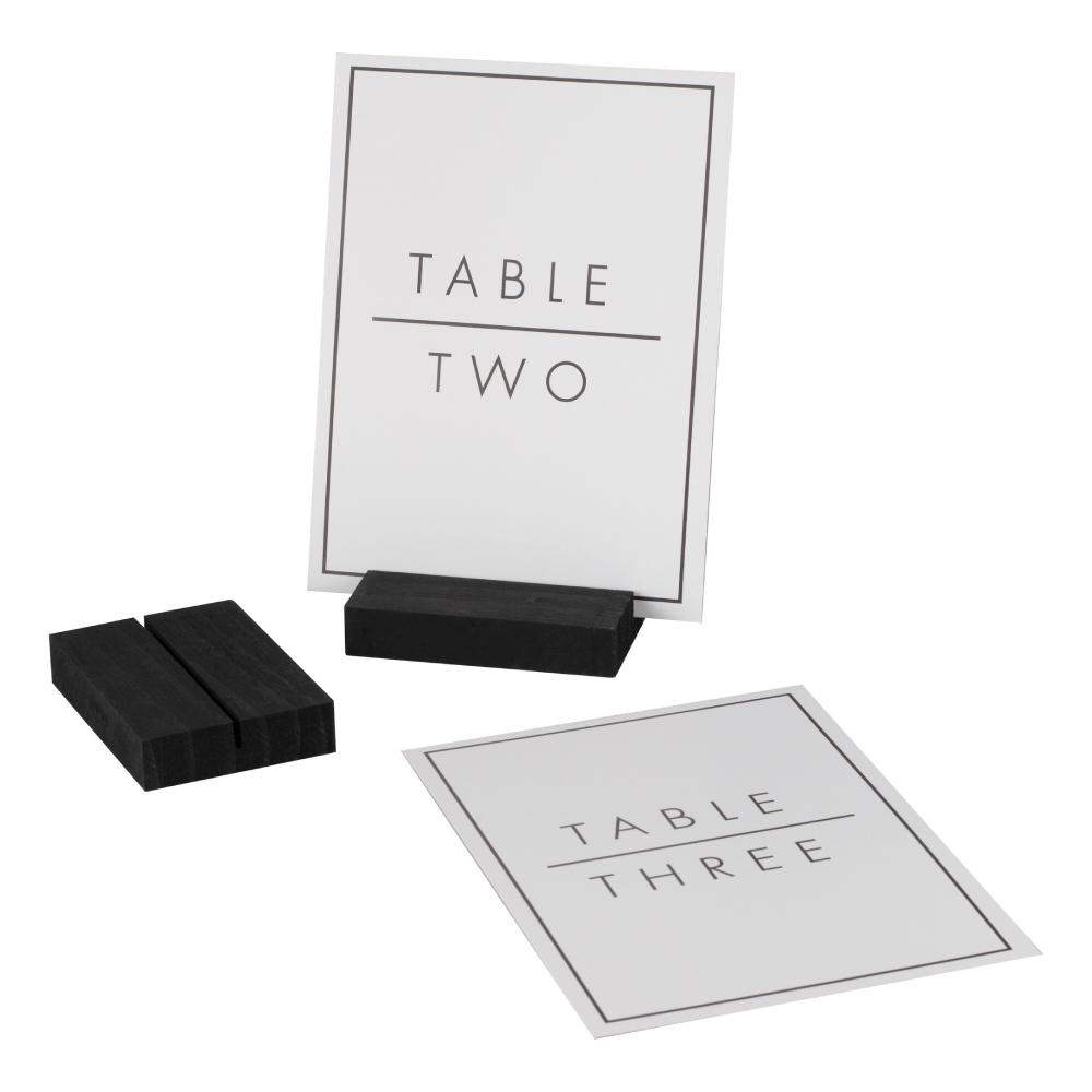 Tafelnummer in het zwart en wit met strakke afwerking staat op een wit tafelkleed versierd met bladgroen