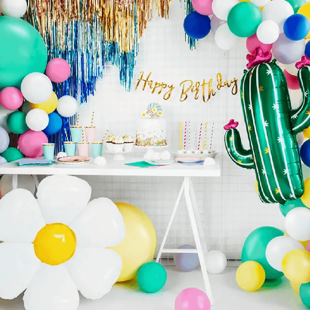 Witte tafel staat tussen gekleurde ballonnen en twee folieballonnen van een madeliefje en een cactus