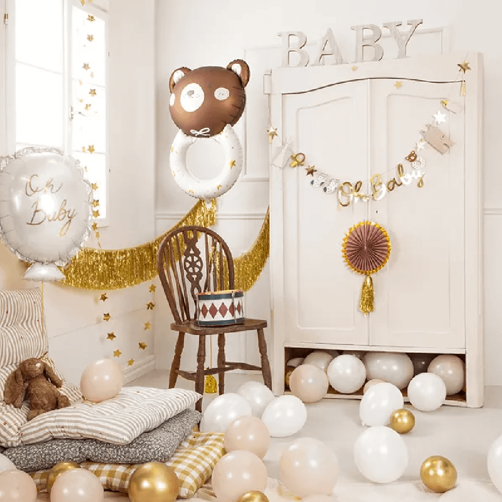 Babykamer met bruine, gouden en beige versiering en een folieballon in de vorm van een beer
