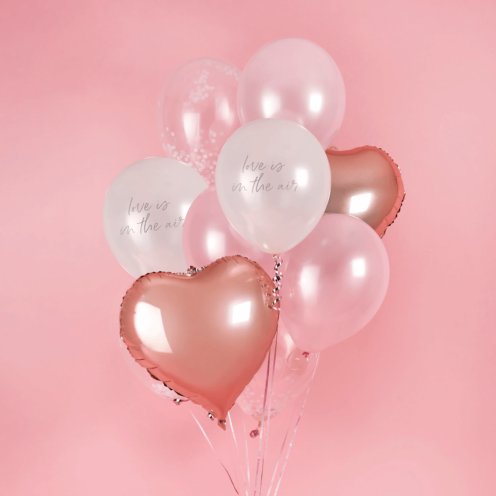 Set ballonnen bestaande uit een hartvormige folieballon, roze confettiballonnen en parelmoer ballonnen met de tekst love is in the air