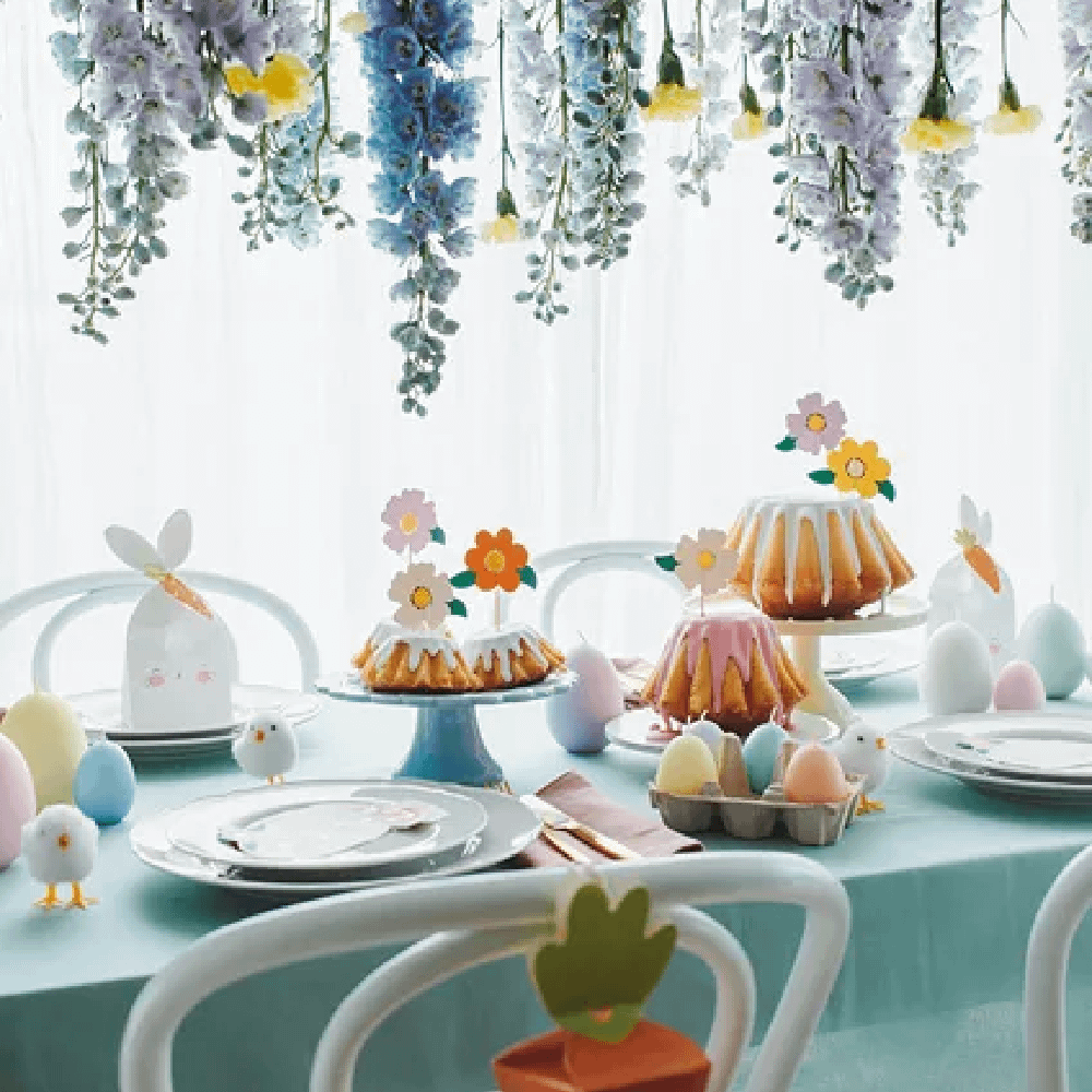 Tafel met blauw tafelkleed versierd met verschillende cakes en gekleurde eieren