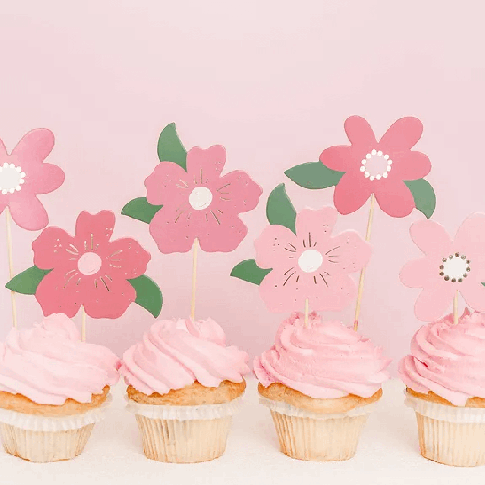 Cupcakes versierd met lichtroze botercreme en roze cupcaketoppers met bloemen