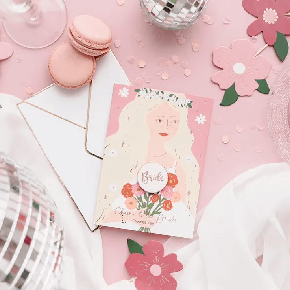 Roze tafel versierd met lichtroze confetti, roze macarons, zilveren discoballen en een kaart met een bruid erop