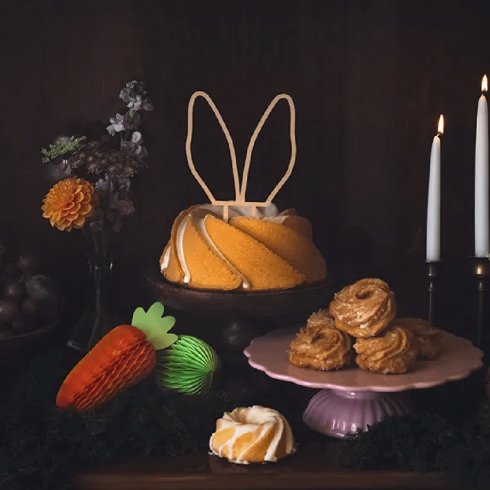 Houten konijnenoren in een cake krans is omringd met honeycombs wortels en paaseieren en een bosje bloemen
