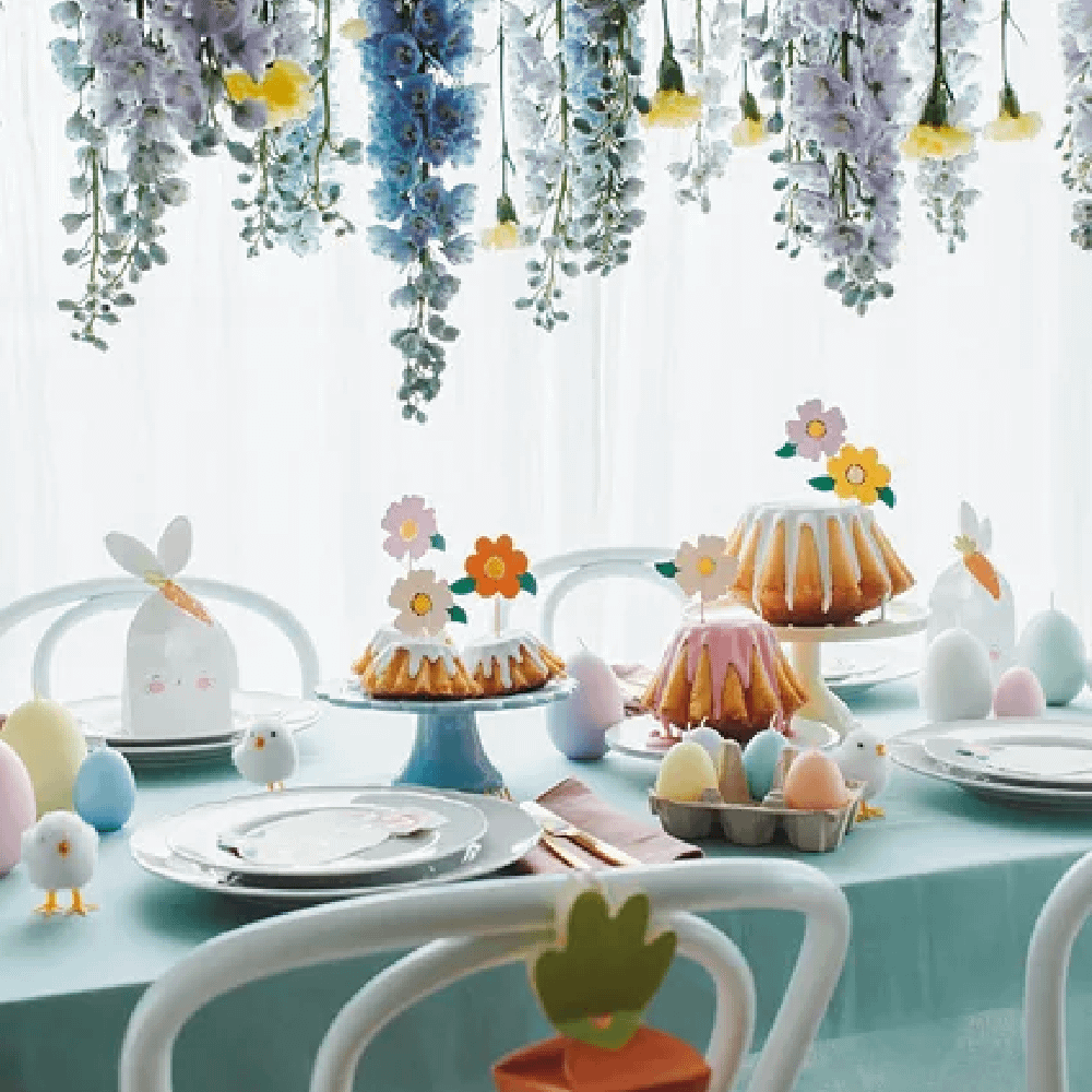 Feesttafel versierd met een ballon in de vorm van een konijn, bloemen die van het plafond afhangen en pastelkleurige paaseieren