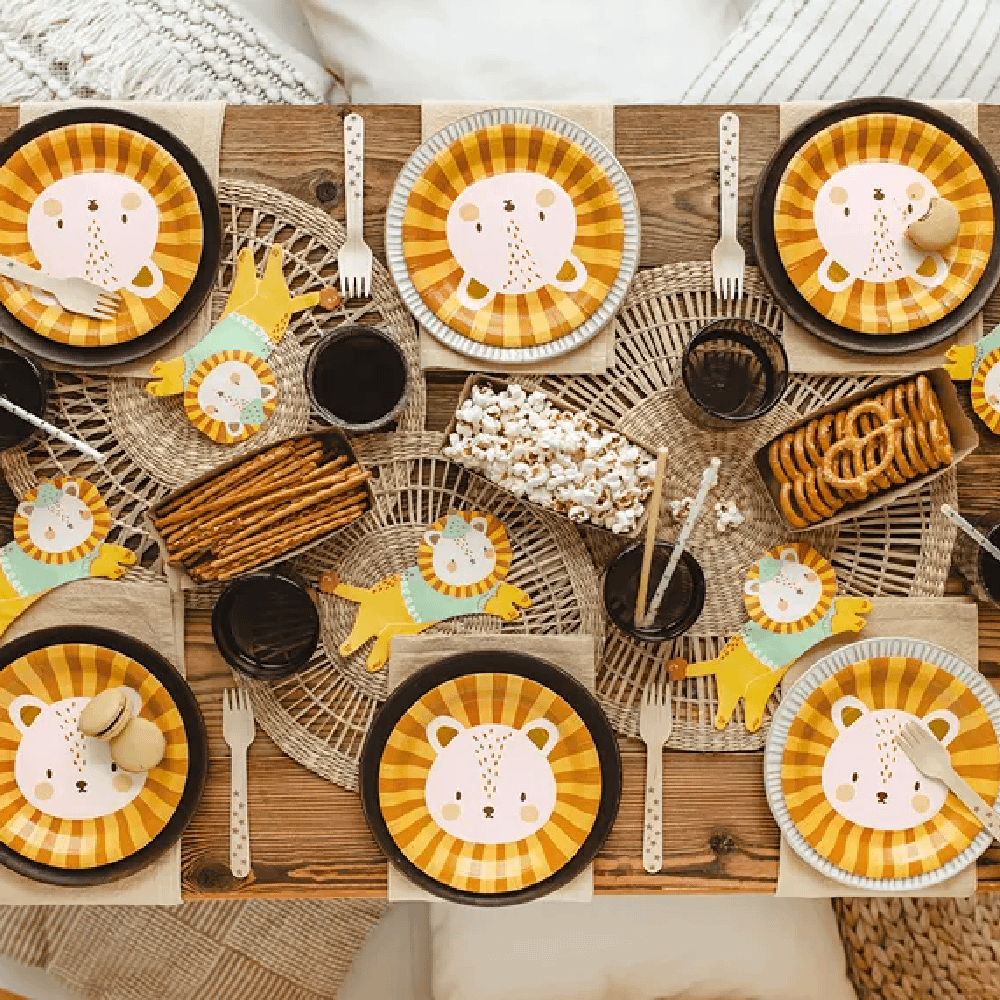 Eettafel versierd met bruine, rieten servetten, papieren bordjes in het oranje en geel en servetten in de vorm van leeuwtjes