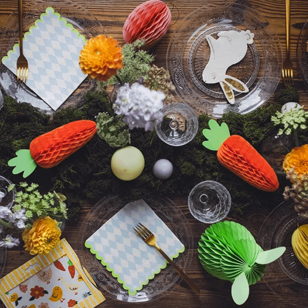 Honeycombs in de vorm van wortels, paaseiere en konijntijes liggen op een donkerbruine houten tafel gevuld met groen mos en glazen borden