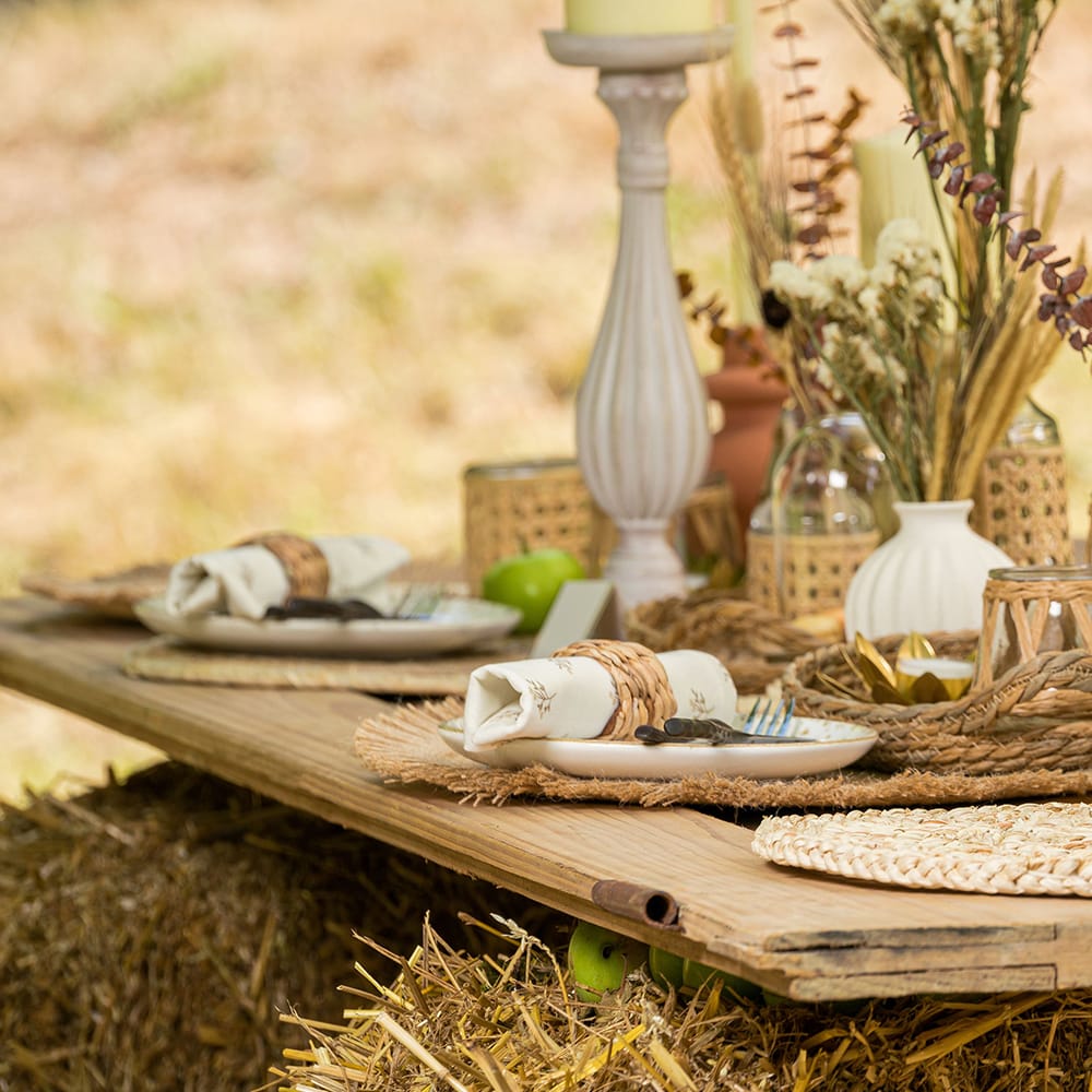 Houten tafel staat in een veld en is versierd met witte borden en droogbloemen