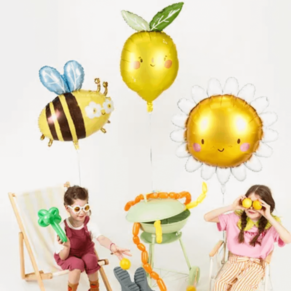 kinderen met folieballonnen in de vorm van een bij, een citroen en een zon