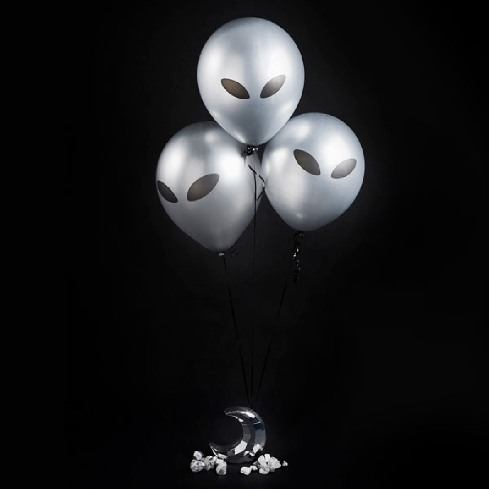 Zilveren ballonnen met aliengezicht zweven aan een halve maan in een zwarte ruimte