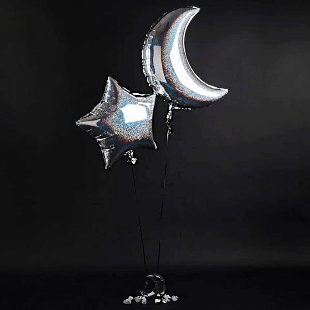 Folieballon in de vorm van een ster en halve maan met een iridescent effect zweven voor een zwarte muur