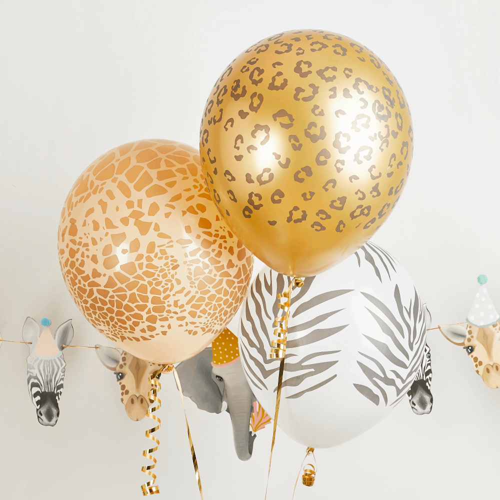 Ballonnen met zebra, tijger en giraffeprint zweven voor een grijze muur met een dierenslinger