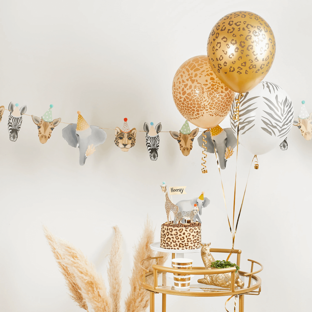Slinger met jungledieren hangt aan een witte muur achter ballonnen met tijgerprint en beige pampas