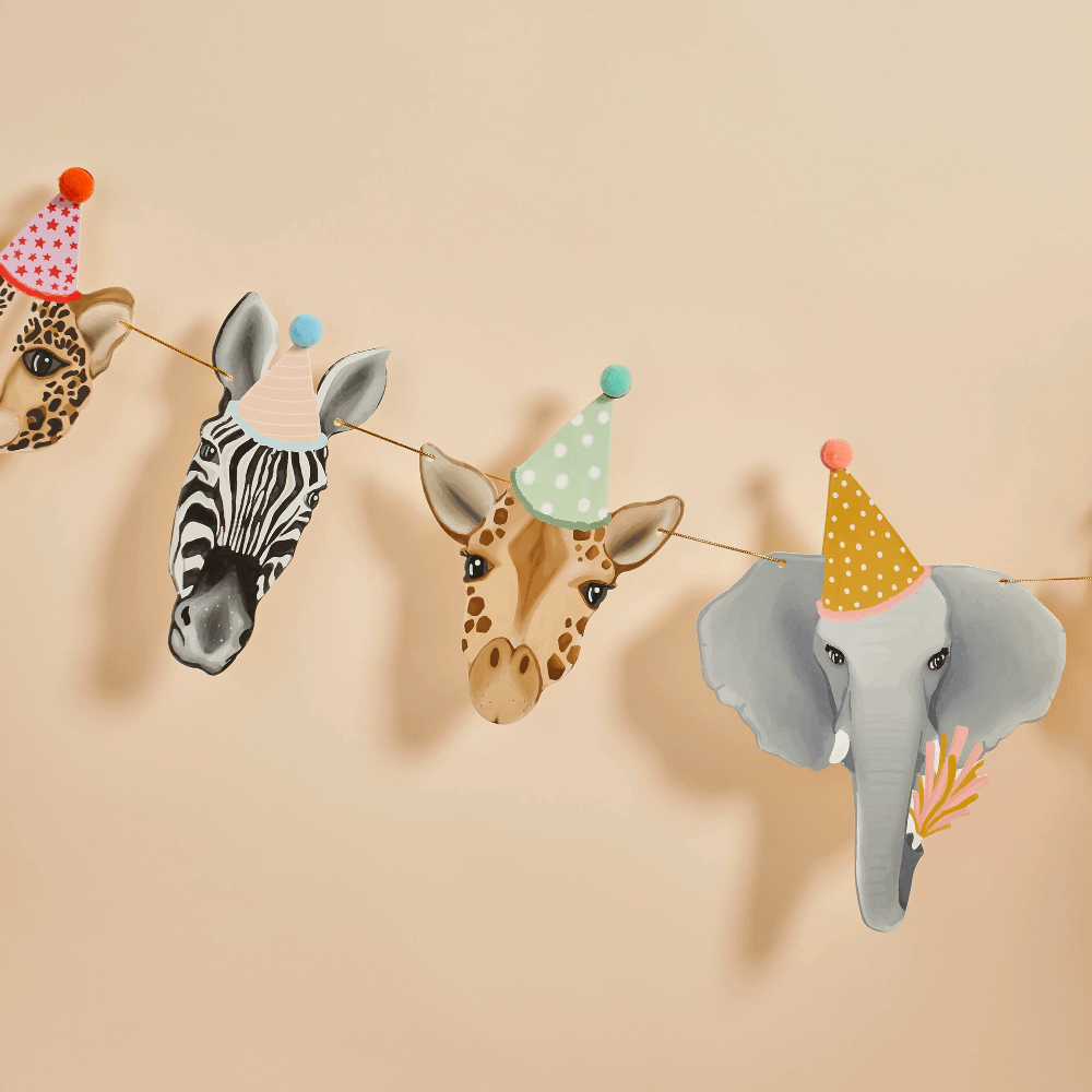 Slinger met jungledieren zoals een olifant, zebra, giraffe en tijger met feesthoedjes op hangt voor een zalmkleurige muur