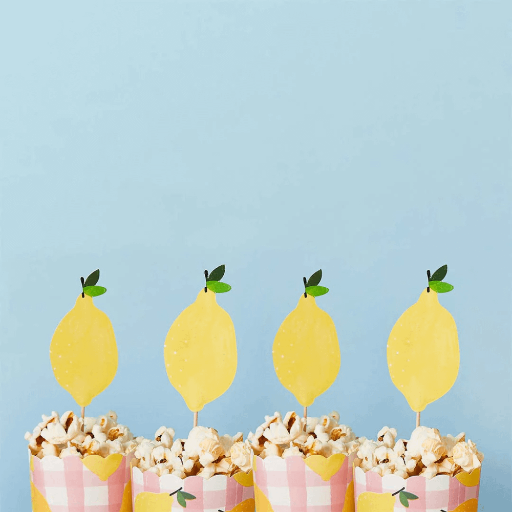 Cocktailprikkers met citroentjes erop zitten in bakjes met popcorn