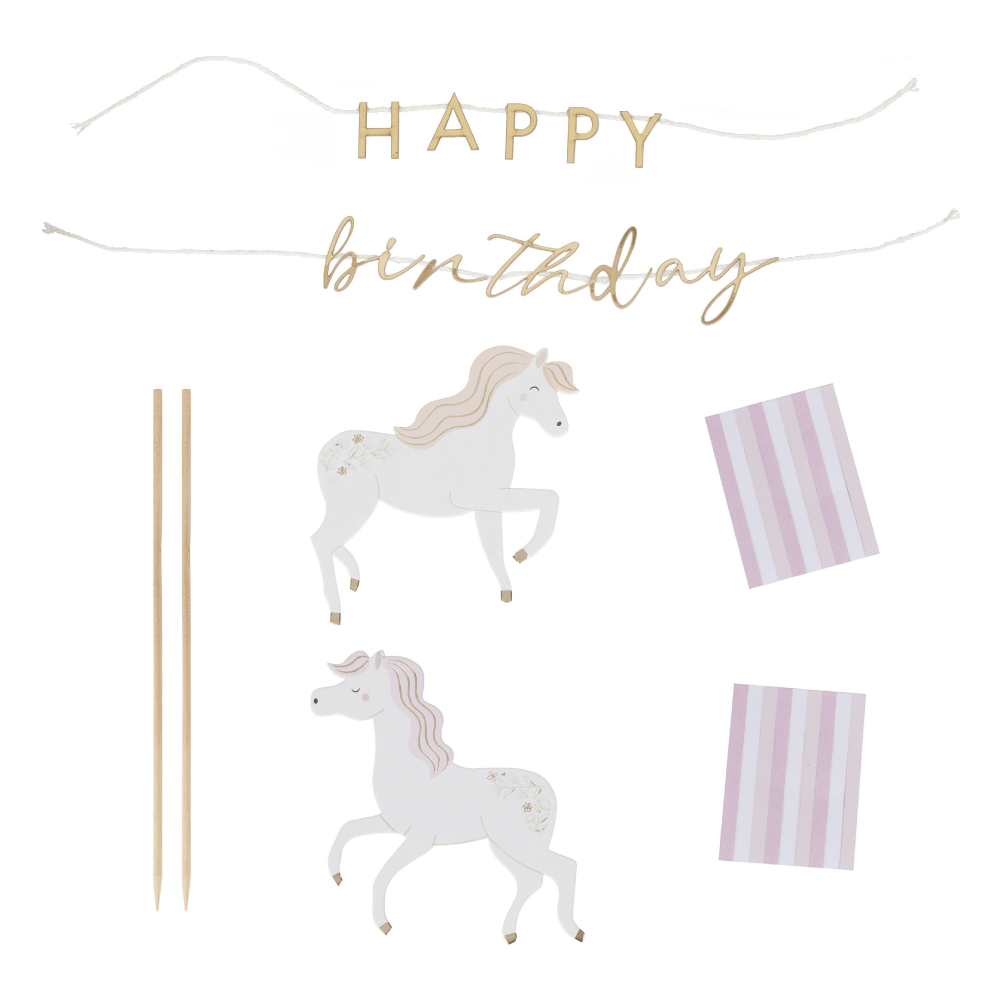 Materialen voor een taart topper met eenhoorns en de gouden tekst happy birthday met roze en witte franjes