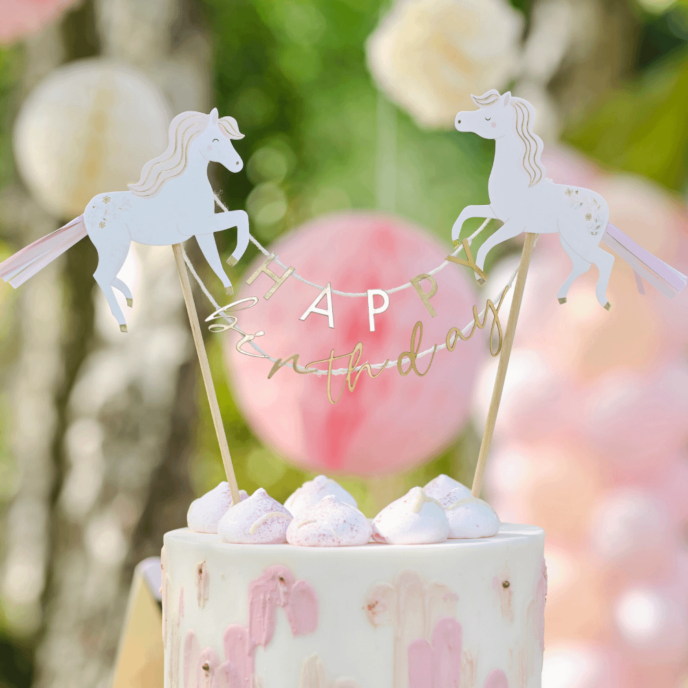 Taart topper met paarden en de gouden tekst happy birthday zit in een beige met roze taart voor een roze honeycombs