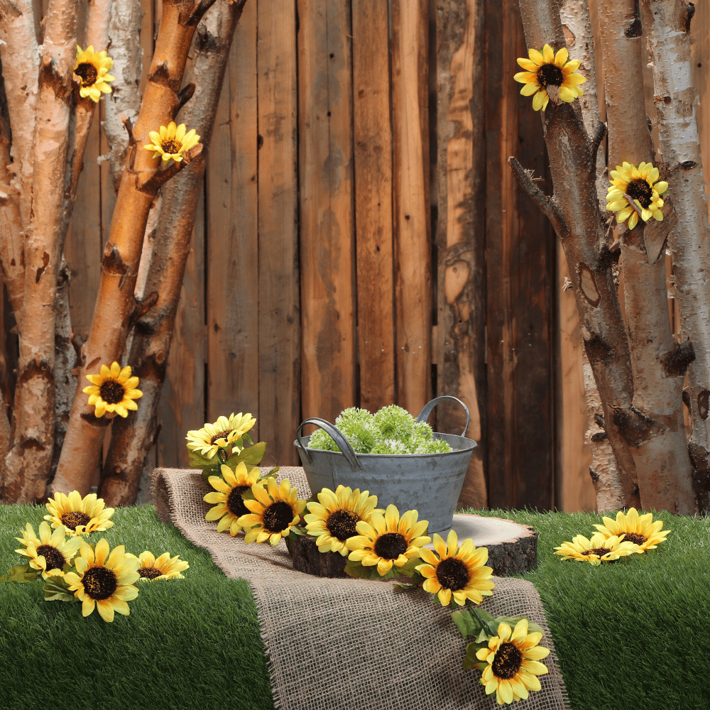 Zonnebloemen slinger ligt op een grasmat voor een houten schutting en houten boomstammen