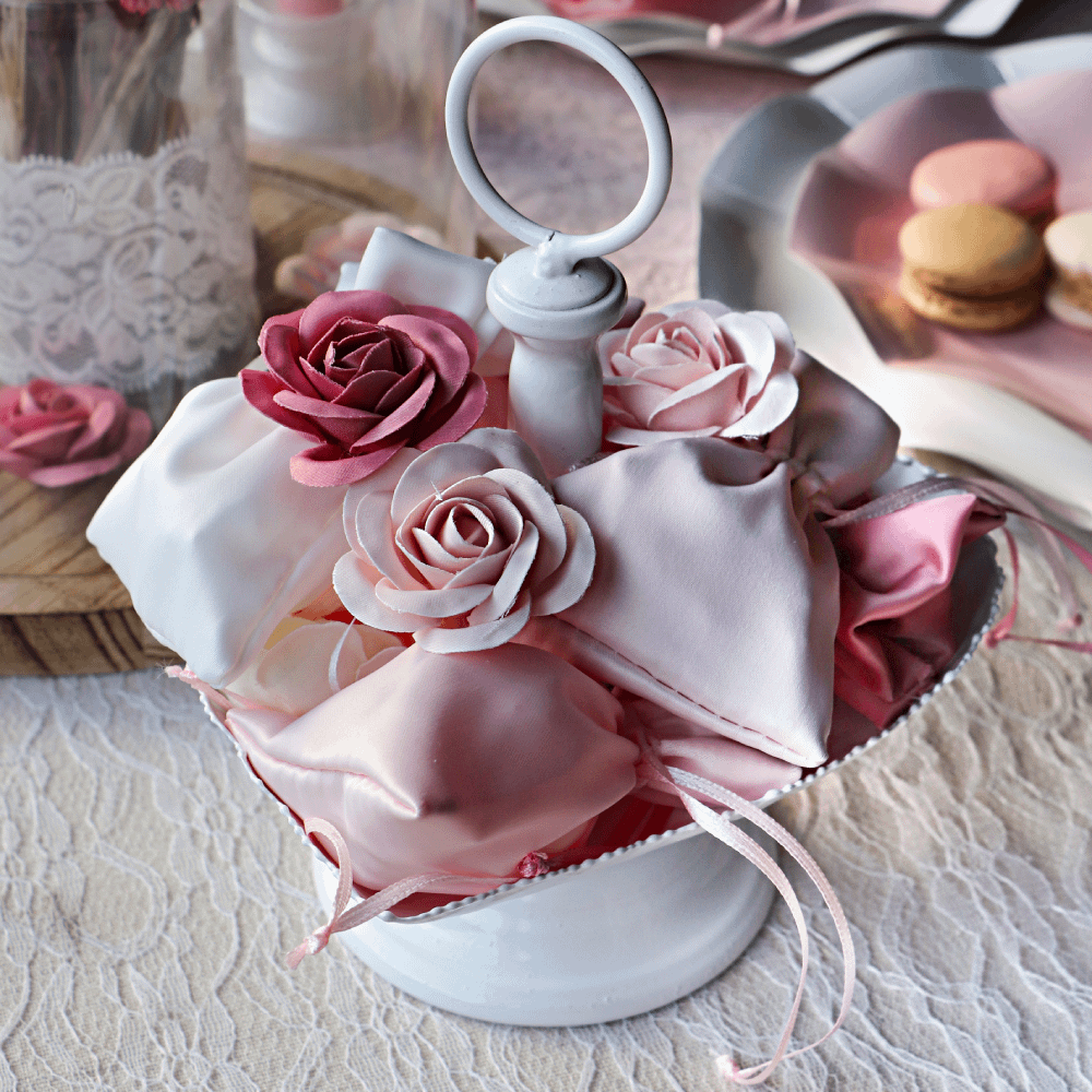 Fuschia en roze roosjes in een wit schaaltje met roze en witte zakjes