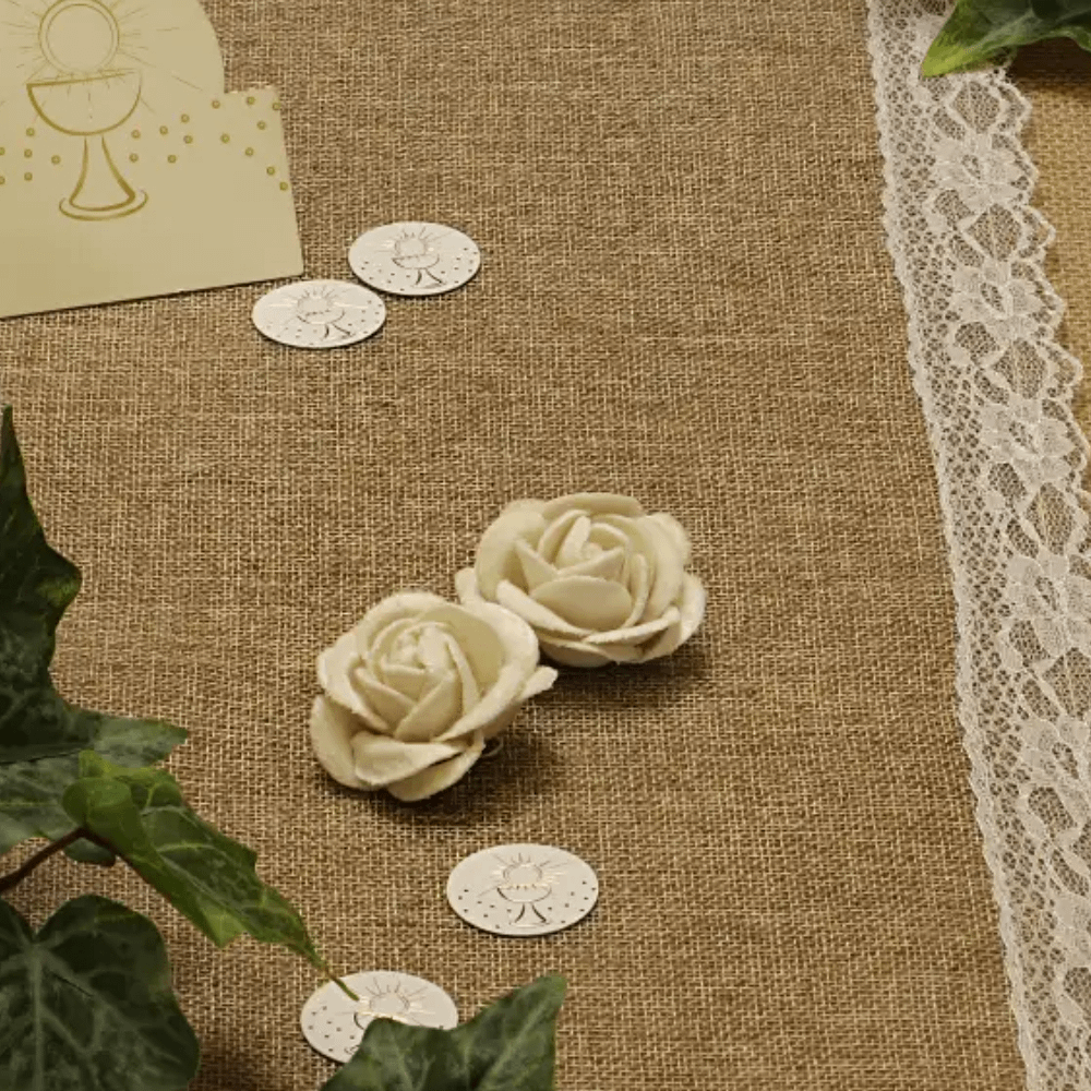 Witte roosjes op een jute met wit kant tafelkleed en groene bladeren