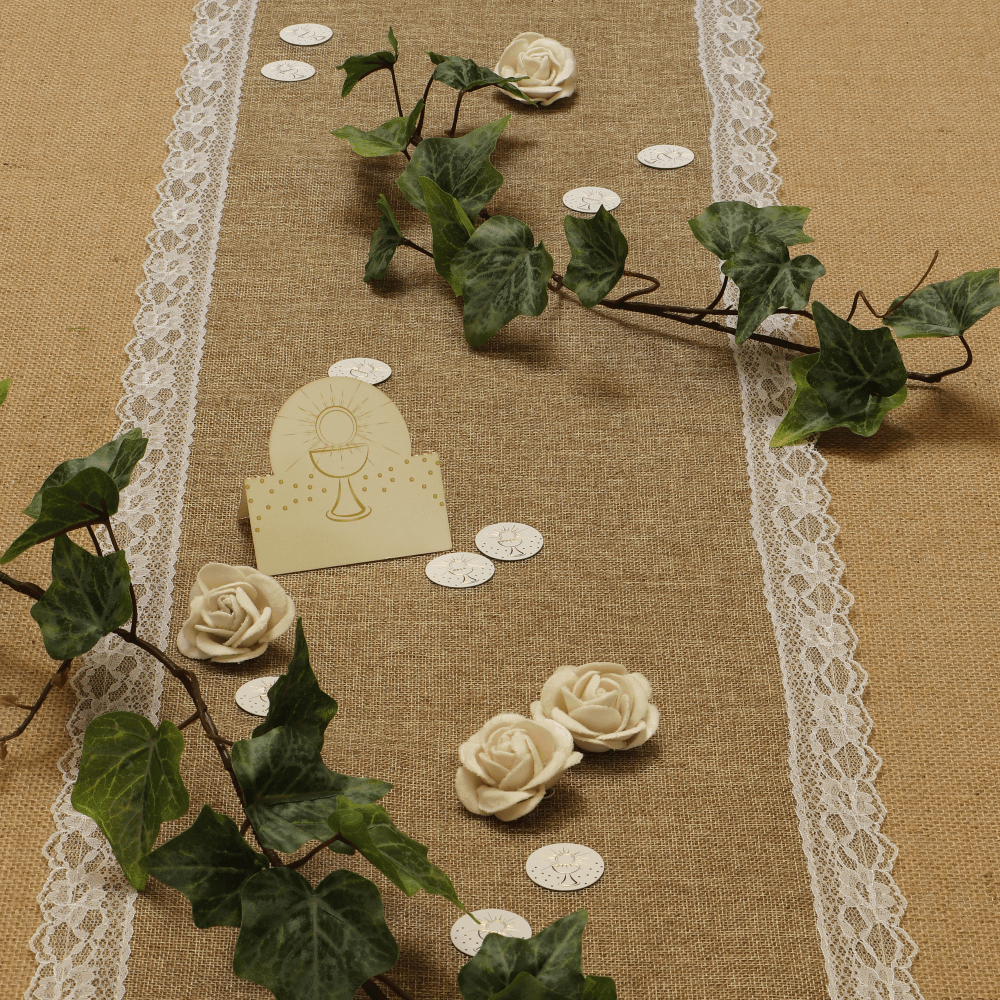 Jute tafelloper met wit kant en groene bladeren is versierd met witte roosjes en confetti voor een communie