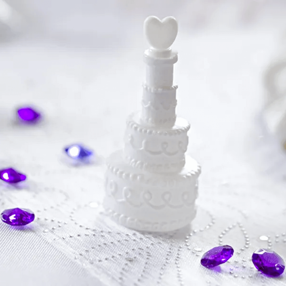 bellenblaas in een potje in de vorm van een trouwtaart op een wit kleed naast paarse diamantjes