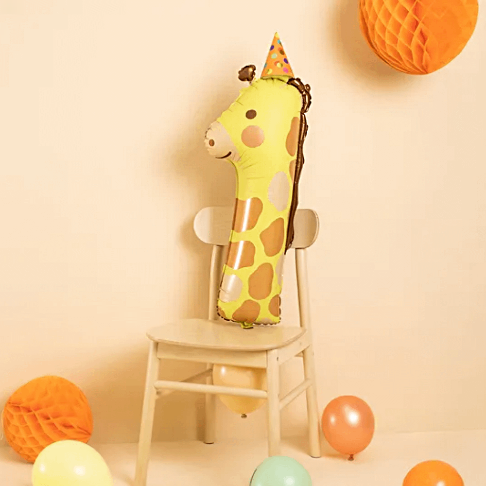 giraffe ballon cijfer 1 ligt po een stoel voor een lichtoranje achtergrond naast honeycombs en ballonnen