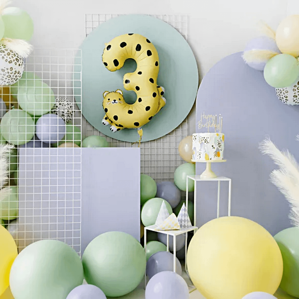 pastelkleurige versiering waaronder ballonnen, een taart en een cijferballon