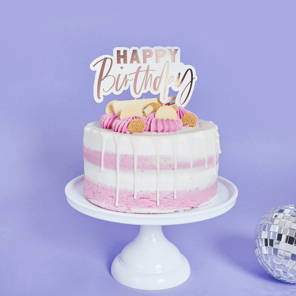 Wit plateau met een roze en witte taart en rose gouden taart topper met de tekst happy birthday