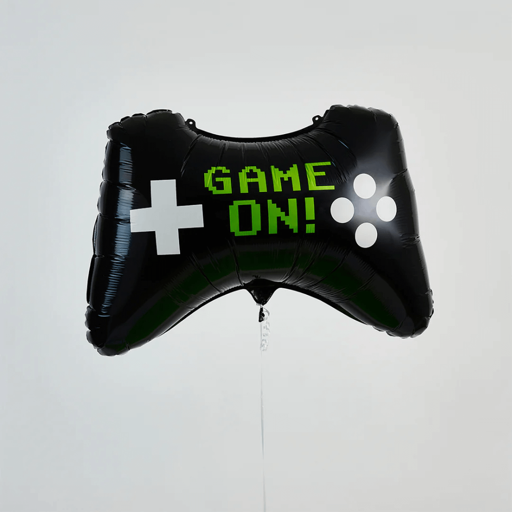 zwarte ballon in de vorm van een controller met de groene tekst game on zweeft voor een lichtgroene muur