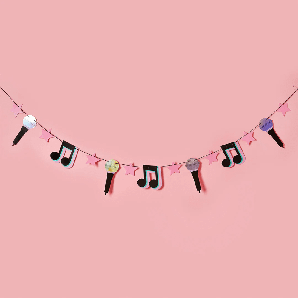 slinger met muzieknootjes, microfoontjes en roze sterren hangt voor een roze muur