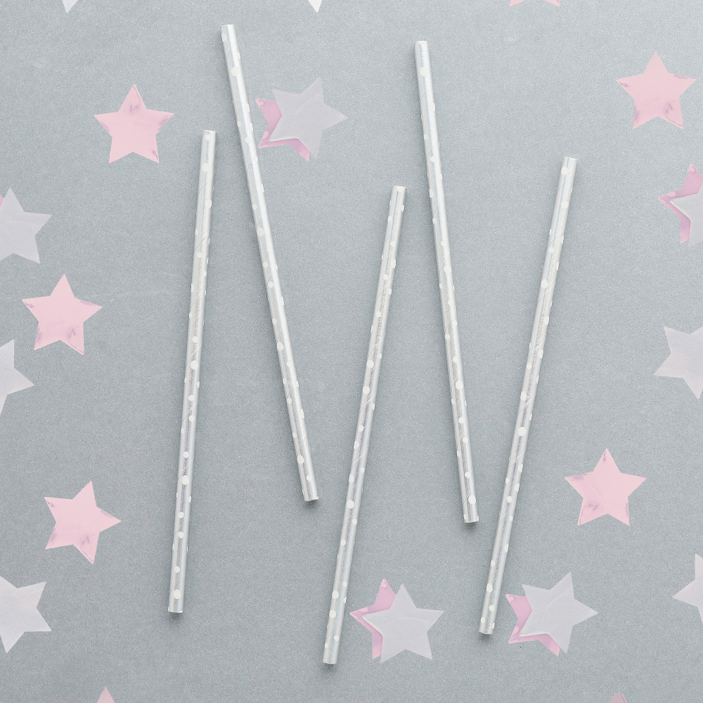 iridescent rietjes met witte stippen liggen op een grijze ondergrond met roze en iridescent sterren