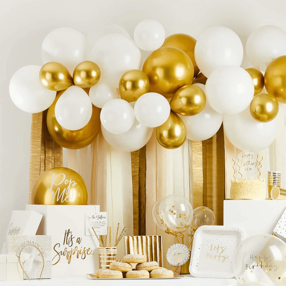 Witte en gouden versiering bestaande uit ballonnen, rietjes, bekers, bordjes en een haarband