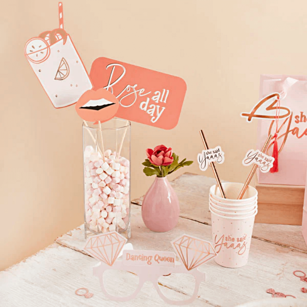 Witte houten tafel met roze vaasje en een vaas gevuld met marhsmallowes en foto accessoires