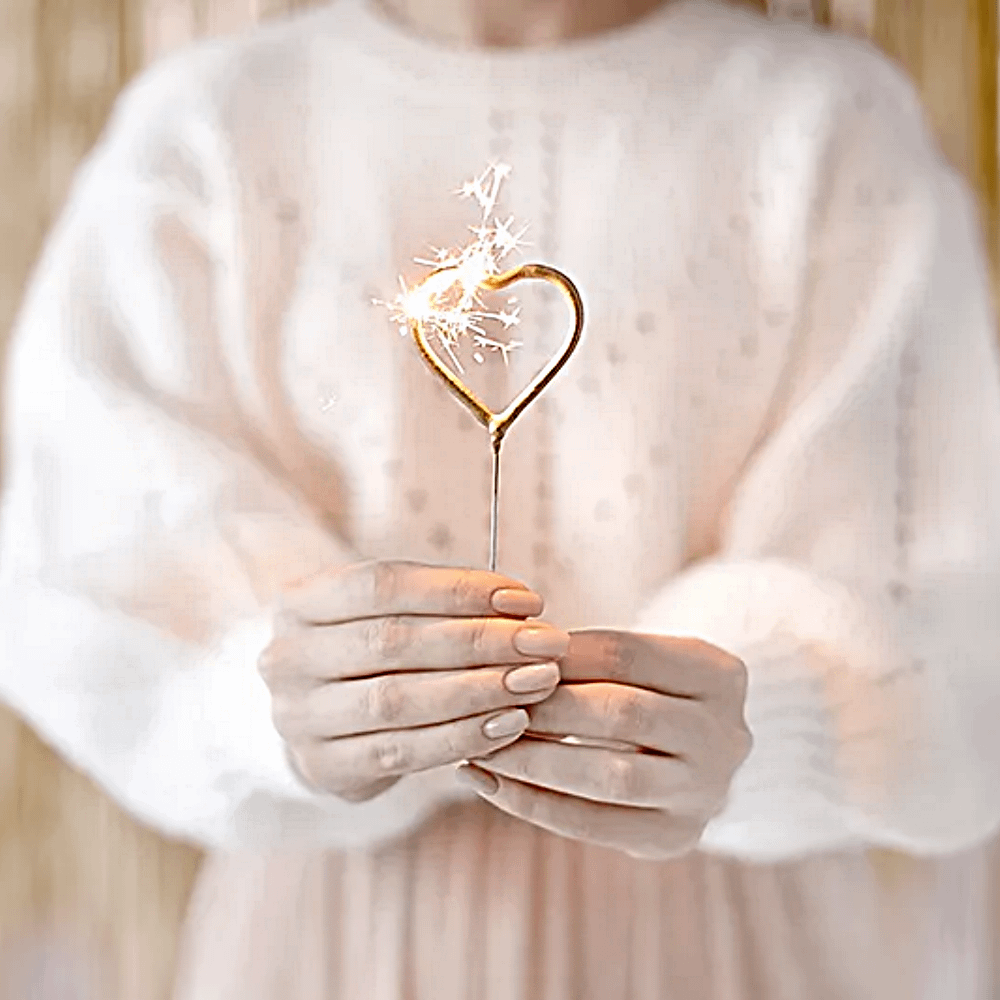 gouden hartjes vuurwerk word vastgehouden door een vrouw in een witte trui