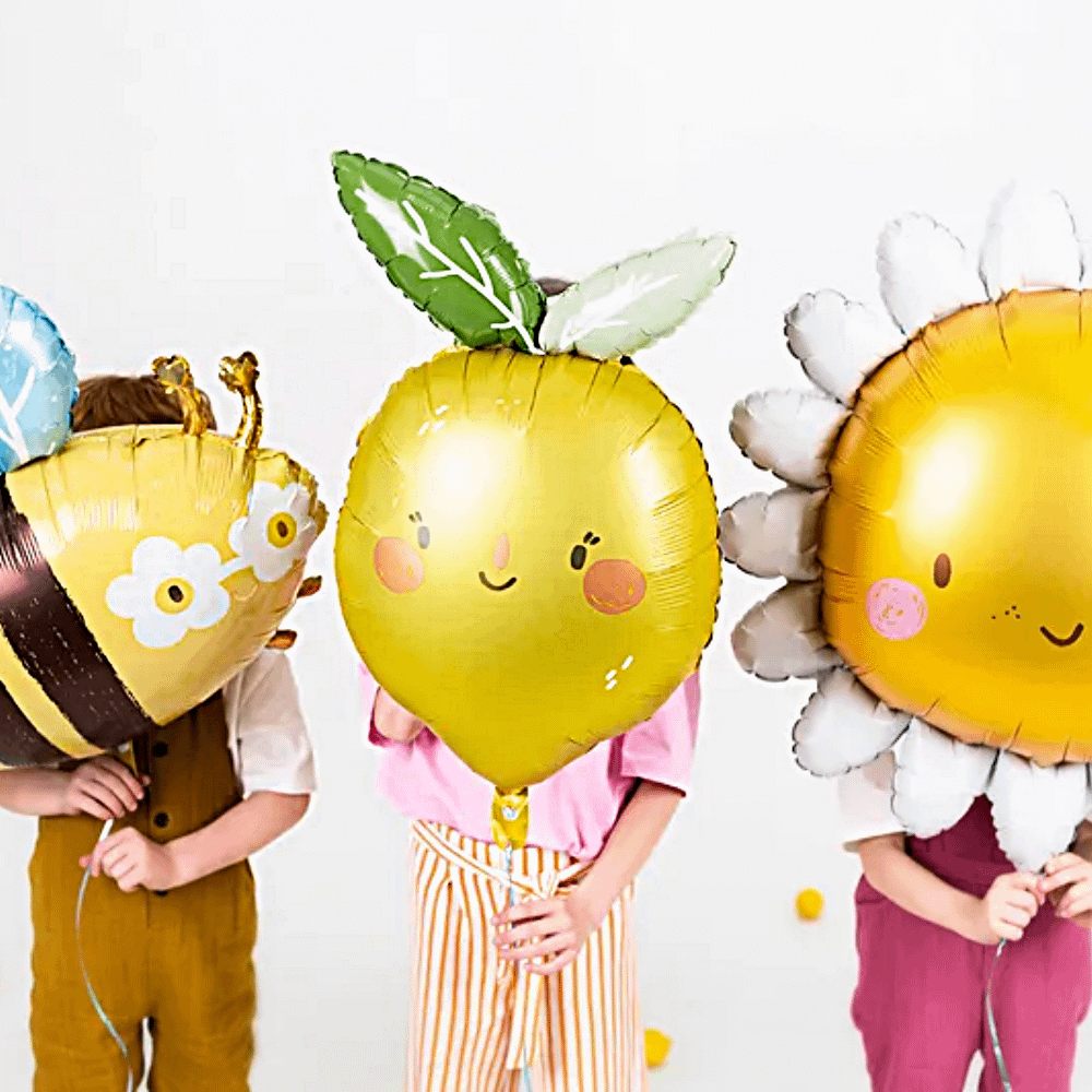 drie kinderen met folieballonnen in de vorm van een citroen, zon en een hommel