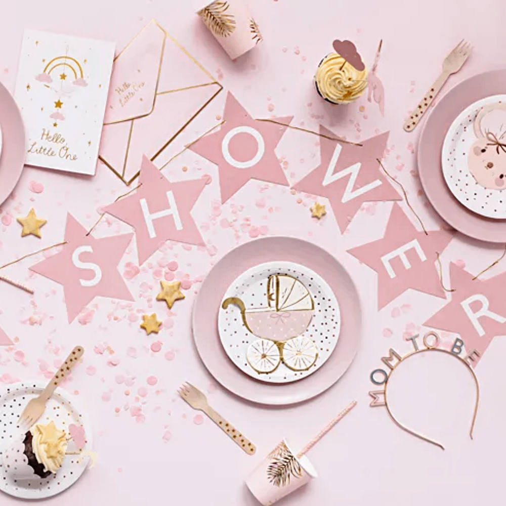 roze tafel versierd met servetten, bordjes en een slinger voor een babyshower meisje
