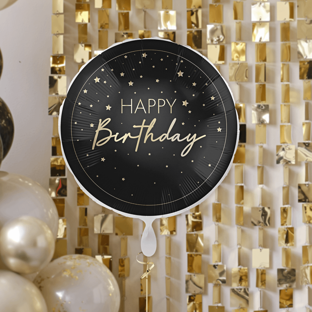 zwarte ronde ballon met gouden sterren en tekst happy birthday en gouden rand zweeft voor een gouden vierkante backdrop