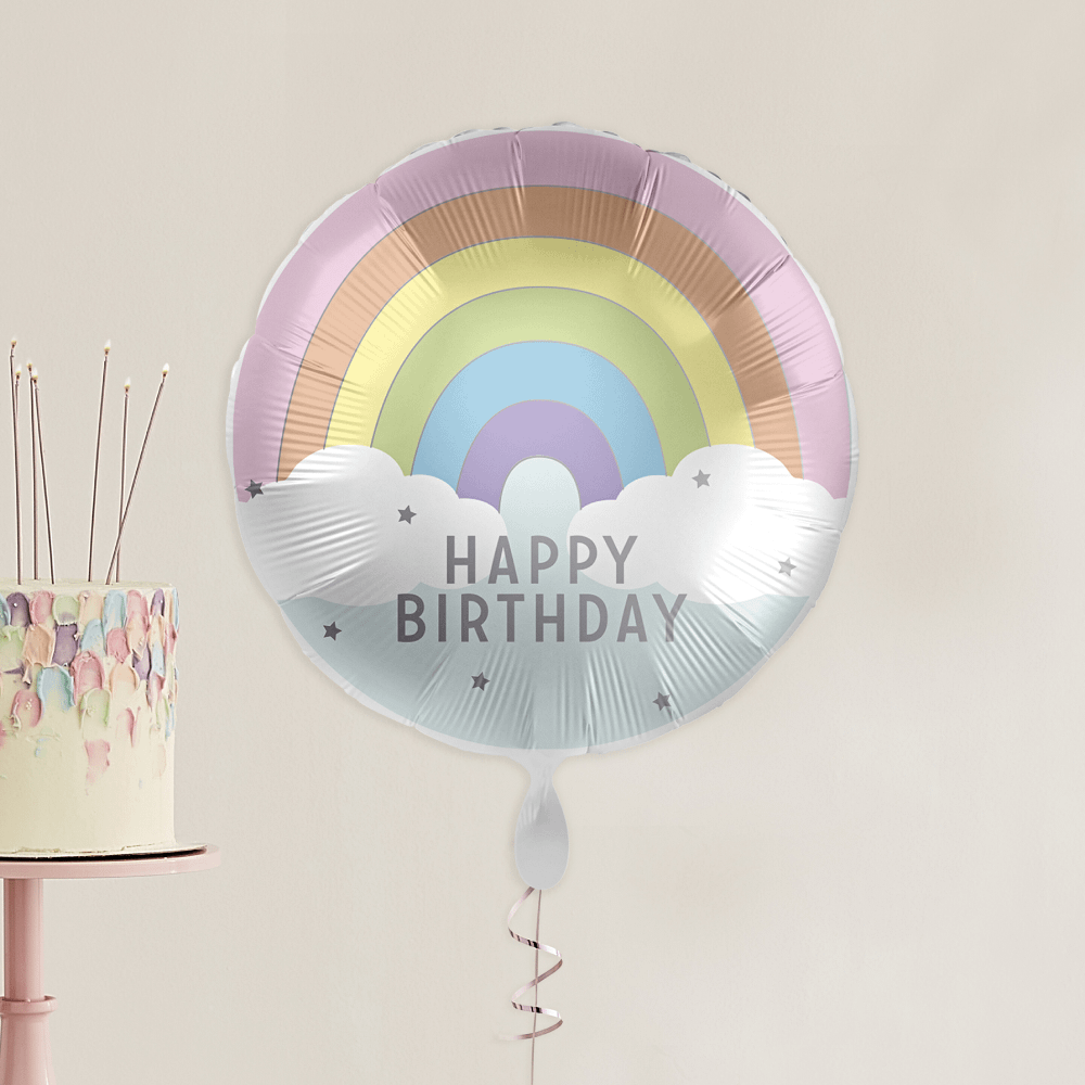 folieballon regenboog en wolken happy birthday zweeft in een kamer voor een witte taart
