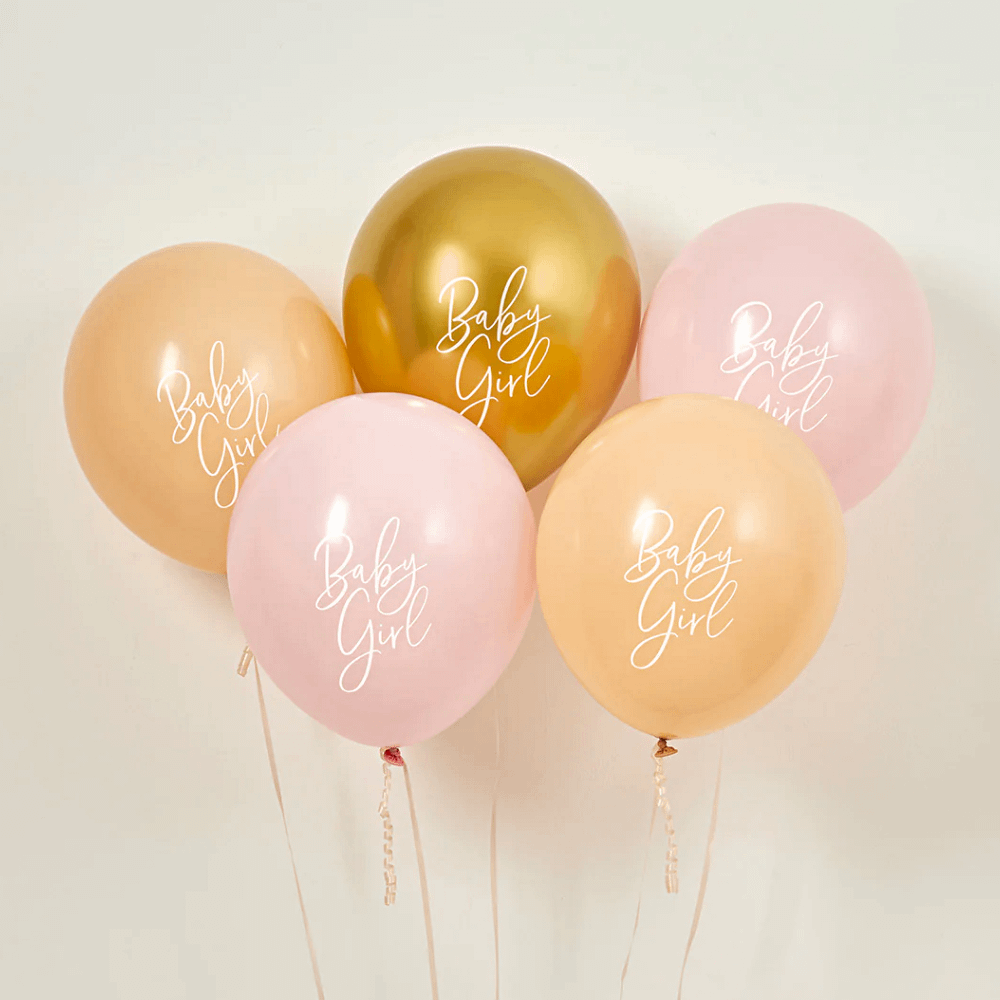 Set ballonnen in het goud, nude en lichtroze met de witte tekst baby girl op een beige muur