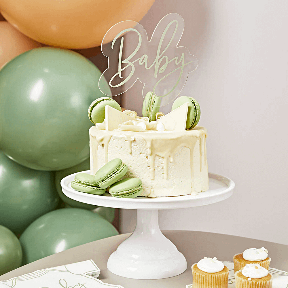 acryl taart topper met de saliegroene tekst baby zit in een beige taart met witte chocola en groene macarons