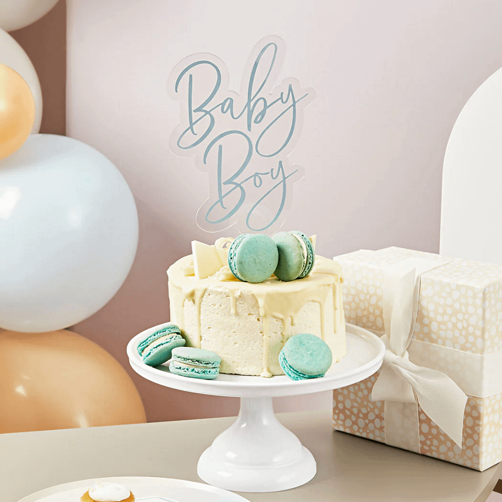 taart topper met de blauwe tekst baby boy in een beige taart met blauwe en groene macarons