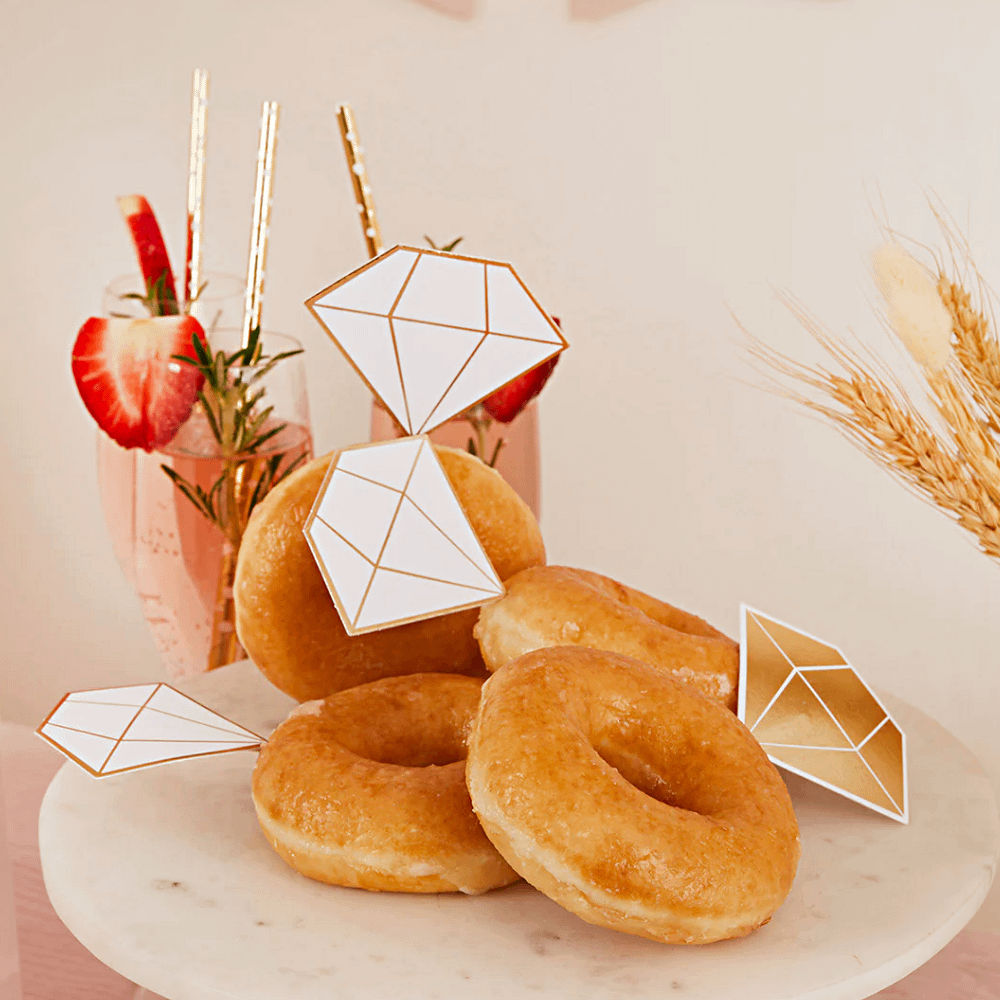 donuts met wit en gouden diamantjes liggen op een witte tafel naast aardbeien