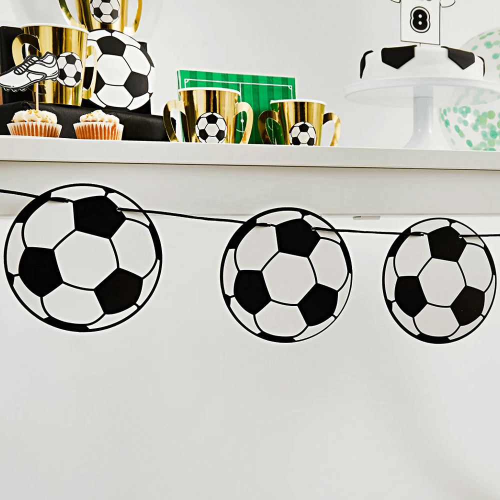 voetbal slinger hangt voor een grijze muur met gouden bekers op een witte plank
