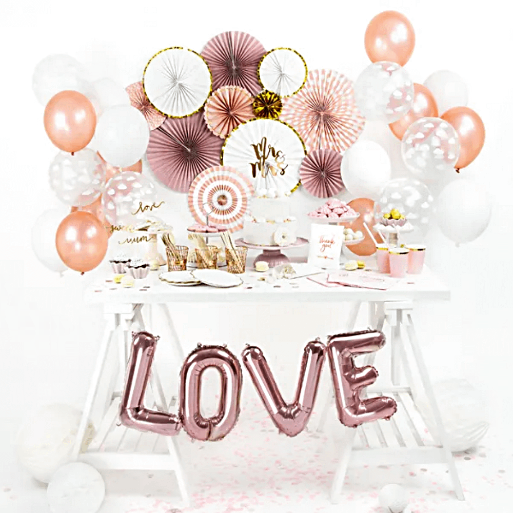 witte tafel met rose gouden versiering en letterballonnen die love spellen
