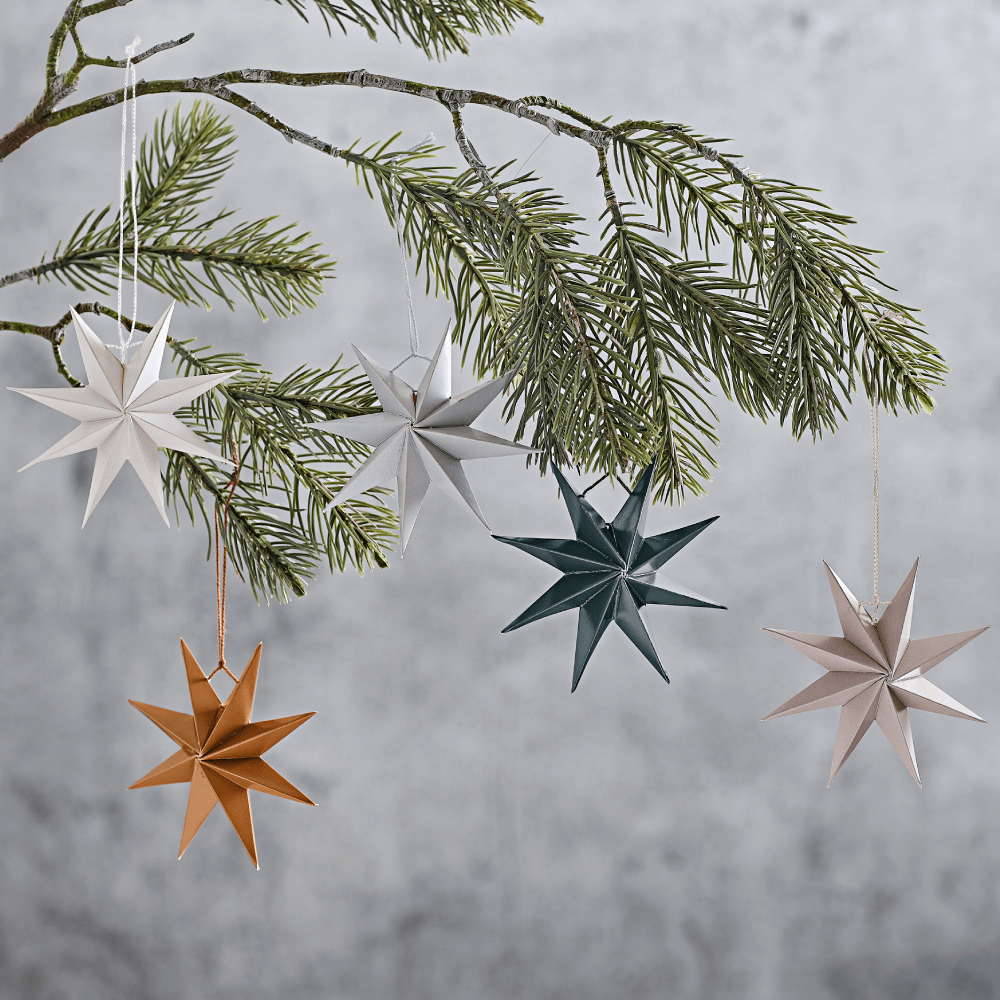 Kerst sterren in het donkergroen, koper, wit, grijs en beige hangen aan een groene kerstboom