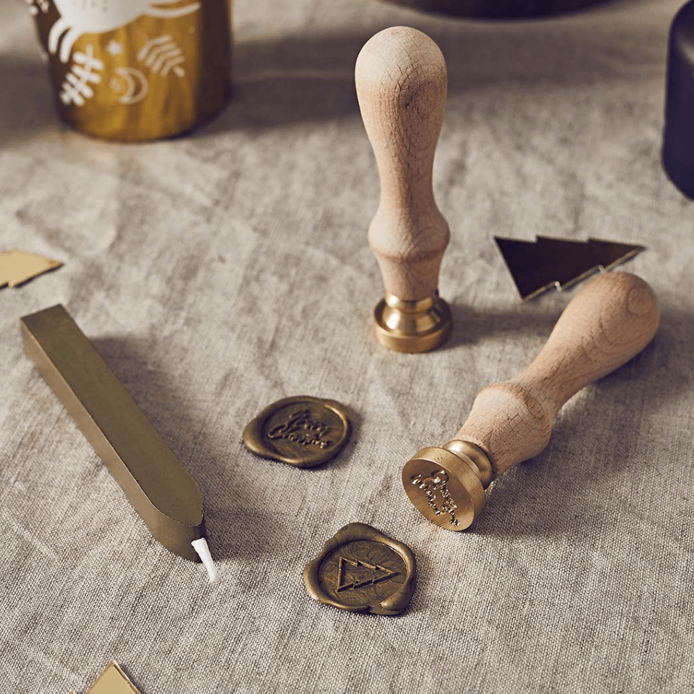 Stempel voor wax met gouden wax en houten handvat staat op een katoenen kleed