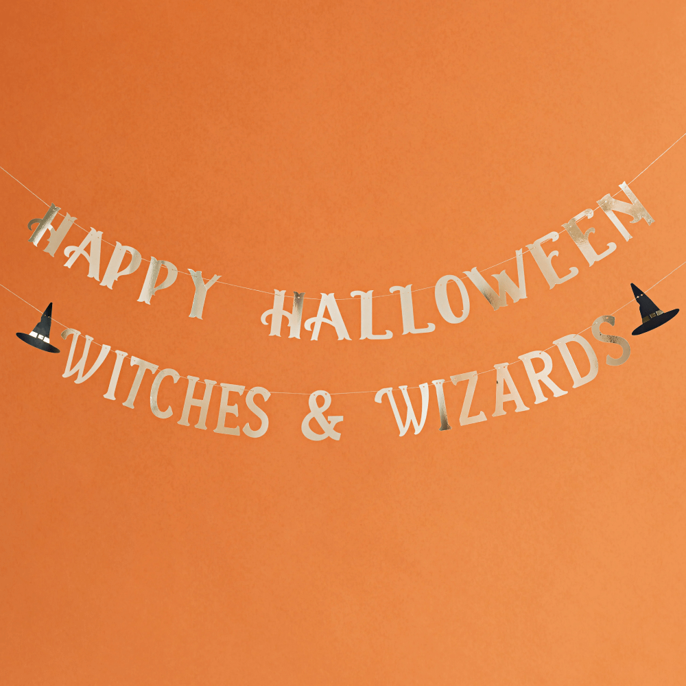 Slinger met gouden tekst happy halloween witches & wizards met een heksenhoed hangt voor een oranje achtergrond