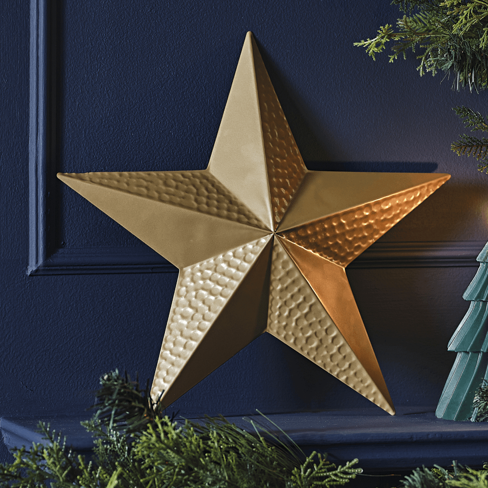 Metalen, gouden ster staat op een donkerblauwe schouw voor een marineblauwe muur